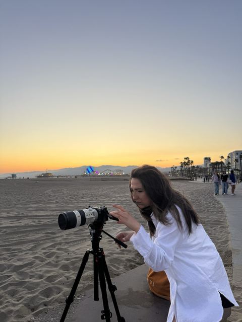 Haya Al Badarneh behind a long lens on a beach at sunset.