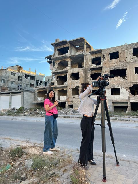 Haya Al Badarneh filming on location beside destroyed buildings in Gaza.
